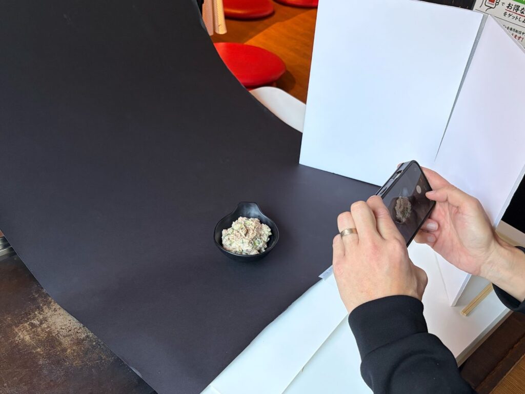 00均のスチレンボードを自作レフ板として右手前に配置し料理の影を消す撮影風景