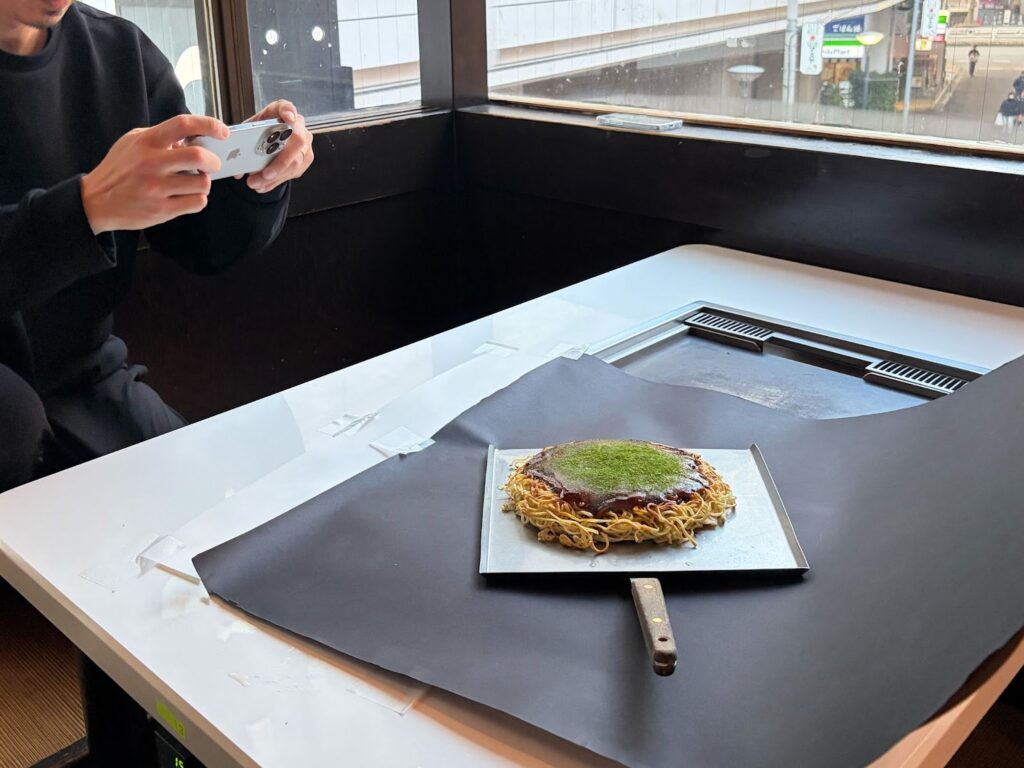 飲食店の明るい窓際で直射日光を避け自然光を活用して料理を撮影する様子